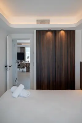 a bedroom with a white bed with a wooden closet at Terrasse Vue Mer - 2BR - Parking - Croisette 50m in Cannes