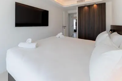 a bedroom with a large white bed with a flat screen tv at Terrasse Vue Mer - 2BR - Parking - Croisette 50m in Cannes