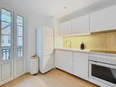a kitchen with white cabinets and a white refrigerator at Repère des Artistes - central, 3mn from Beach, 10mn Palais, modern, AC, balcony in Cannes