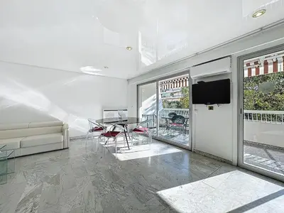 a living room with a table and chairs and a television at Rue d'Antibes Victoria 2 rooms terrace - 2ES in Cannes