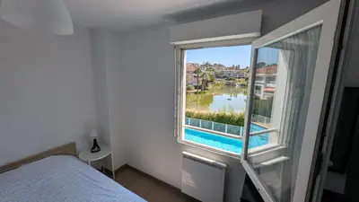 a bedroom with a window with a view of the water at Pleasant bright apartment - lake and pool view in Le Cannet