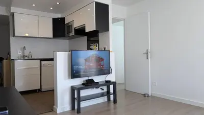 a living room with a tv and a kitchen at Pleasant bright apartment - lake and pool view in Le Cannet