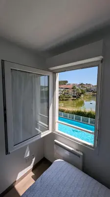 a bedroom with a window with a view of a pool at Pleasant bright apartment - lake and pool view in Le Cannet