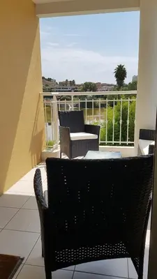 a balcony with a table and chairs on a patio at Pleasant bright apartment - lake and pool view in Le Cannet