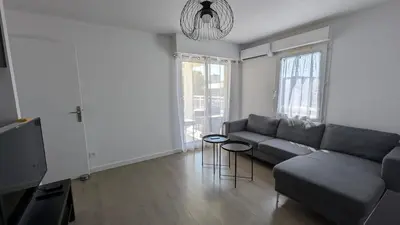 a living room with a couch and a tv at Pleasant bright apartment - lake and pool view in Le Cannet