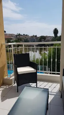 a patio with a chair and a table on a balcony at Pleasant bright apartment - lake and pool view in Le Cannet