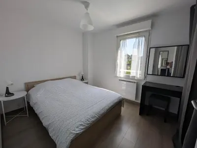 a bedroom with a bed and a desk and a window at Pleasant bright apartment - lake and pool view in Le Cannet