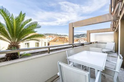 a balcony with a table and chairs and a palm tree at 64 ANTIBES - Stunning 1-bedroom with terrace at Gray d'Albion in Cannes