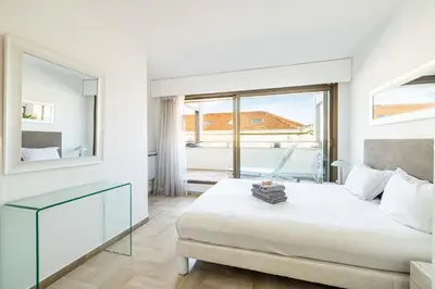 a white bedroom with a bed and a large window at 64 ANTIBES - Stunning 1-bedroom with terrace at Gray d'Albion in Cannes