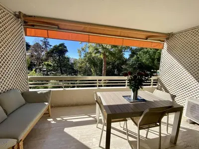 a patio with a table and a couch on a balcony at Cannes - Magnifique 4 pièces terrasse au calme à deux pas de la rue d'Antibes in Cannes