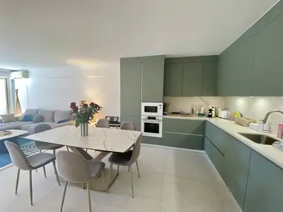 a kitchen and living room with a table and chairs at Cannes - Magnifique 4 pièces terrasse au calme à deux pas de la rue d'Antibes in Cannes