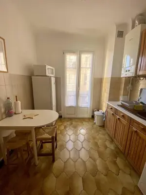 a small kitchen with a table and a refrigerator at Cannes proche Croisette - 2 pièces lumineux in Cannes