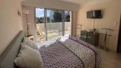 a bedroom with a bed and a balcony with a television at Chez Marilyne & Jean Baptise in Cannes