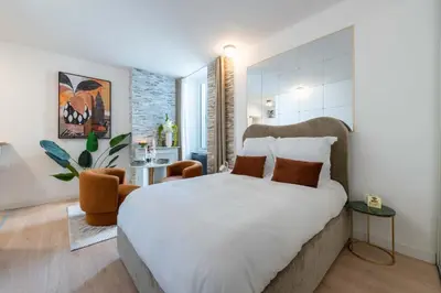 a bedroom with a large bed and a chair at Studio design au centre de Cannes proche Croisette climatisé in Cannes