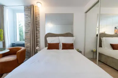 a bedroom with a large white bed and a chair at Studio design au centre de Cannes proche Croisette climatisé in Cannes