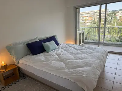 a bed in a room with a large window at Spacious 2-bedroom sea view with parking in Palm Beach in Cannes
