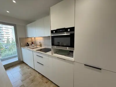 a kitchen with white cabinets and a microwave at Spacious 2-bedroom sea view with parking in Palm Beach in Cannes