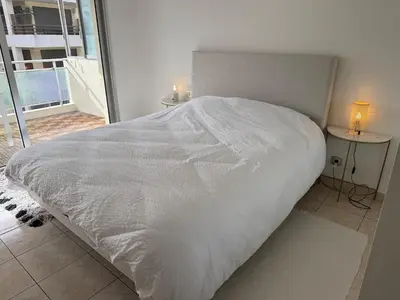 a white bed in a bedroom with a window at Spacious 2-bedroom sea view with parking in Palm Beach in Cannes