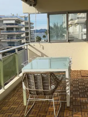 a glass table and a chair on a balcony at Spacious 2-bedroom sea view with parking in Palm Beach in Cannes