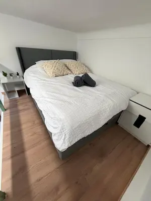 a bedroom with a bed with white sheets and a wooden floor at Studio Moderne à 10 min à pied Palais & Plages in Cannes