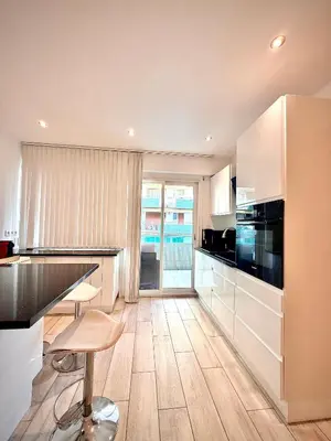 a kitchen with white cabinets and a black counter top at Luxury Cannes Suite Terrace Walk to Palais in Cannes