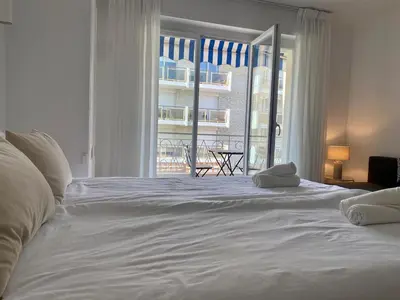a large white bed in a bedroom with a window at Coastal Retreat Studios with Balcony in Cannes