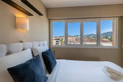 a bedroom with a white bed with a large window at Two bed - Walk to the beach in Cannes