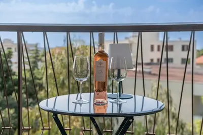 two wine glasses and a bottle on a table on a balcony at Two bed - Walk to the beach in Cannes