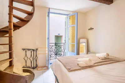 a bedroom with a bed and a spiral staircase at Charming 1-Bedroom Townhouse in Cannes