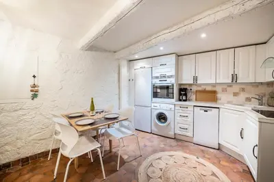 a kitchen with white cabinets and a table and chairs at Charming 1-Bedroom Townhouse in Cannes