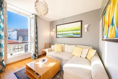 a living room with a white couch and a large window at Two Bedrooms - 250m to the beach in Cannes