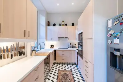 a kitchen with white cabinets and a checkered floor at Private Garden 3-Bed in Cannes in Cannes