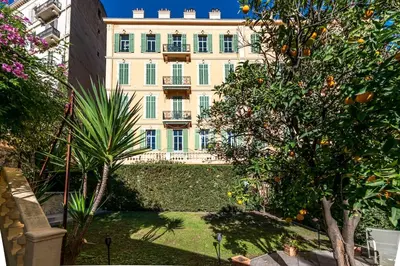a large building in the middle of a garden with trees at Private Garden 3-Bed in Cannes in Cannes