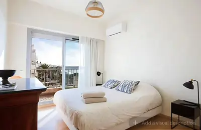 a white bedroom with a bed and a large window at Croisette Top Floor 2BR with Bay View Balcony in Cannes