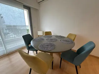 a dining room with a table and chairs and a window at Croisette Top Floor 2BR with Bay View Balcony in Cannes