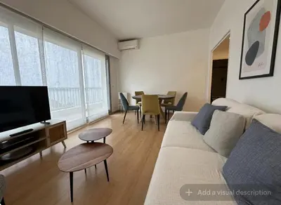 a living room with a couch and a tv and a table at Croisette Top Floor 2BR with Bay View Balcony in Cannes
