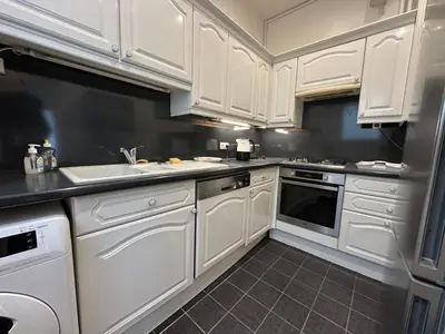 a white kitchen with white cabinets and a sink at Croisette Top Floor 2BR with Bay View Balcony in Cannes