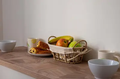 a basket of fruit on a table with two cups at 2-Br Apartment with Terrace Near Cannes Centre in Cannes