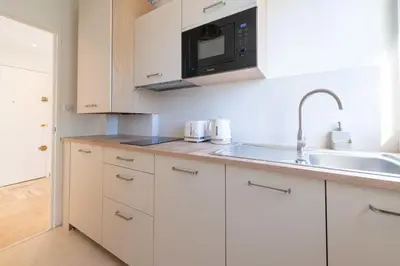 a kitchen with white cabinets and a sink and a microwave at 2-Br Apartment with Terrace Near Cannes Centre in Cannes