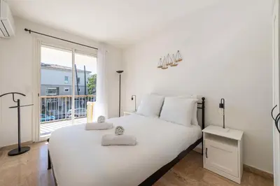 a white bedroom with a large bed and a balcony at 2-Br Apartment with Terrace Near Cannes Centre in Cannes