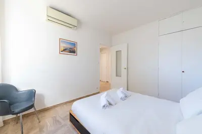 a white bedroom with a bed and a chair at 2-Br Apartment with Terrace Near Cannes Centre in Cannes
