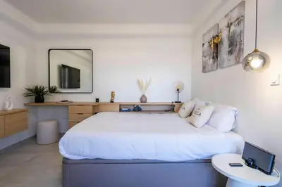 a white bedroom with a large bed and a mirror at L'HARMONIE DE CARNOT avec Balcon in Cannes