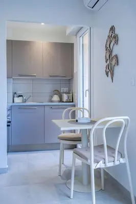 a white kitchen with a table and chairs in it at L'HARMONIE DE CARNOT avec Balcon in Cannes