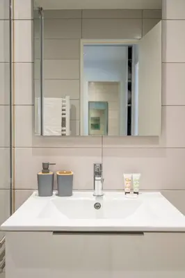a bathroom with a white sink and a mirror at L'HARMONIE DE CARNOT avec Balcon in Cannes