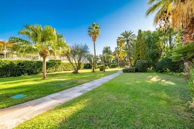 a garden with palm trees and a path at KEM15 Appartement avec vue mer in Cannes