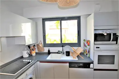 a white kitchen with a sink and a window at air-conditionned apartment 2 bedrooms & bathrooms with refined decoration in Cannes