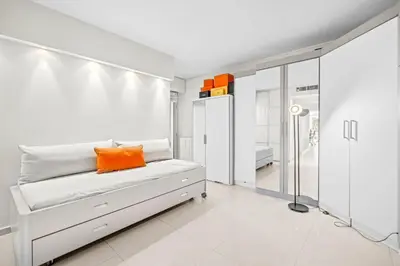 a white bedroom with an orange pillow on a bed at REF 2052 - Seasonal rental - Prestigious apartment on the Croisette Cannes in Cannes