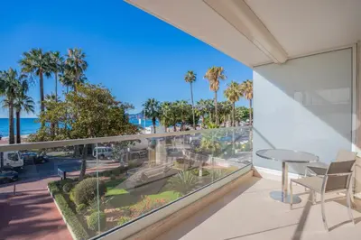 a balcony with a view of the beach and palm trees at REF 2052 - Seasonal rental - Prestigious apartment on the Croisette Cannes in Cannes