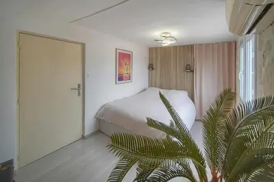 a bedroom with a white bed and a palm tree at Cannes hyper centre -palais du festival -croisette -quartier historique du suquet in Cannes