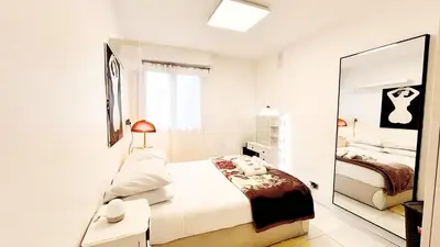 a white bedroom with a bed and a mirror at Proche Centre ville, 1 chambre, balcon - Palmazur Vacances in Le Cannet